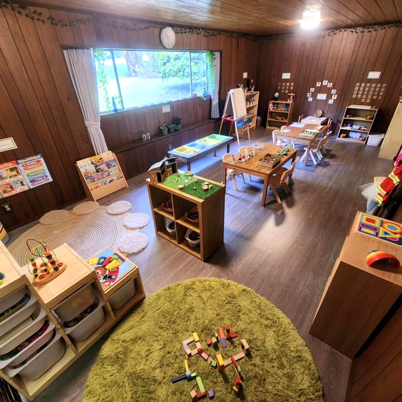 The Indigo Meadow classroom: wooden shelves, low tables, a reading corner and a big window onto the garden