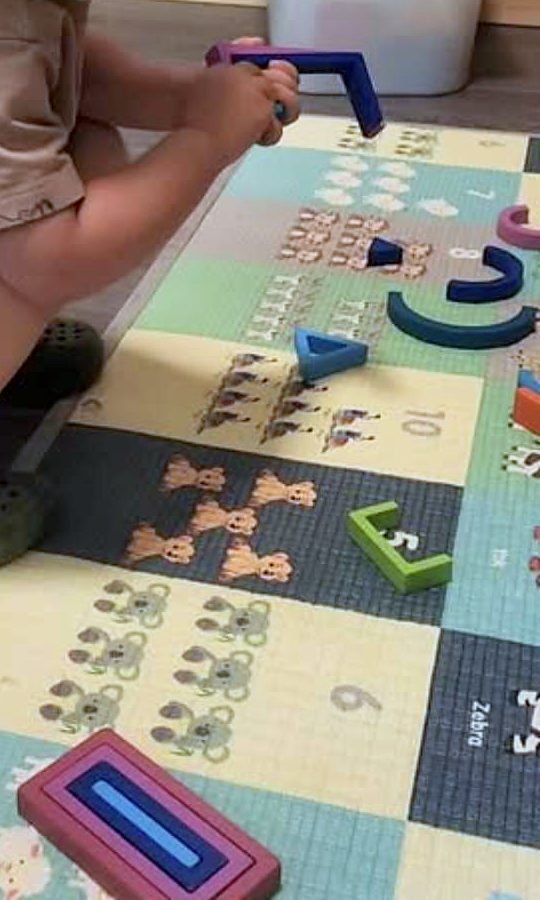A child sorting coloured shapes on a number mat